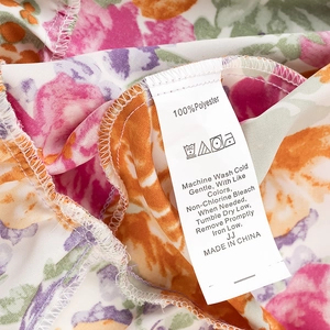 Gros plan détaillé du tissu 100% polyester et de l'étiquette sur la robe à fleurs