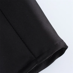 Gros plan sur la texture du tissu sergé noir et les coutures précises de la robe