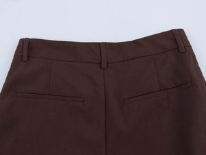Detail of dark brown pleated trousers showing rear waistband and welt pocket design
