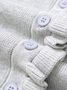 Close-up of soft knit gray fabric with lavender trim and round resin buttons