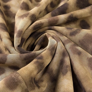 Gros plan du tissu mesh à imprimé léopard montrant la texture ajourée et le drapé doux