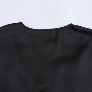 Gros plan du col en V et du tissu en satin lisse de la robe mi-longue noire chic