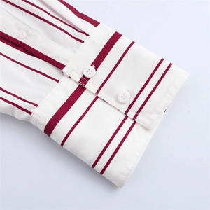 Detalle del puño de camisa con rayas rojas y doble botonadura en tela de popelina