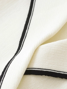 Macro view of white knitted fabric texture with elegant black stripe edge detail
