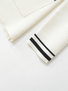 Detail of white knit blazer showing pocket edge and black striped cuffs with fine texture