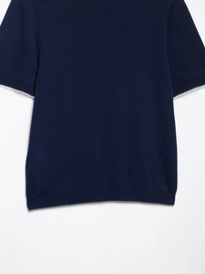 Détail du haut en tricot bleu marine avec manches à bords festonnés blancs élégants