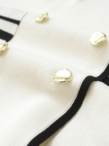 Detailed macro view of white knit fabric with gold decorative buttons and black piping