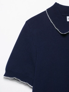 Gros plan sur un haut en tricot bleu marine avec d'élégants bords ondulés blancs sur le col
