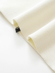 Close-up of cream knit fabric texture with contrasting black label detail for women blazer