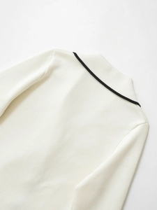 Detailed view of cream knitted cardigan with black contrast trim on the collar