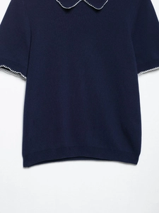 Détail du haut en tricot bleu marine avec bordures en dentelle blanche au col et manches