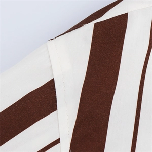 Detalle de la costura del hombro en una camisa de rayas verticales marrón y blanco