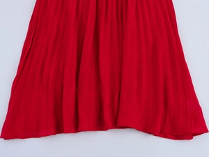 Detail of red pleated long dress showing fine accordion pleats and lightweight fabric texture