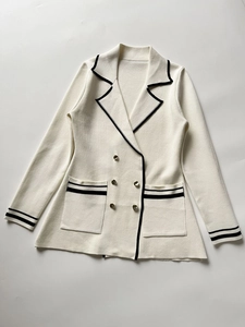 Close-up of knit blazer with black contrast trim and decorative gold embossed buttons