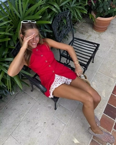 Detail view of red sleeveless button-up vest paired with chic polka dot shorts and sunglasses