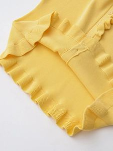 Detailed view of the bright yellow knit cardigan with ruffled hem and matching buttons