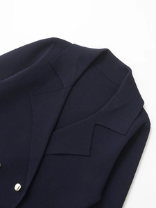 Close-up of dark blue knit blazer featuring golden round buttons and premium fabric texture