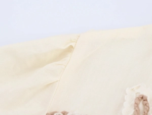Detail of cream cotton linen fabric with delicate lace trim and shoulder pleat stitching