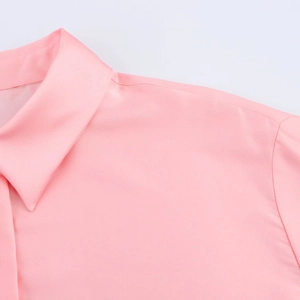 Vue détaillée du tissu en satin brillant et des coutures de l'épaule de cette chemise rose