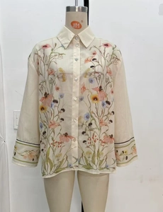 Detail of loose floral print cream blouse showing button-down front and cotton linen texture
