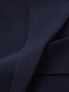 Close-up of premium navy blue knitted fabric showing fine texture and sewing details