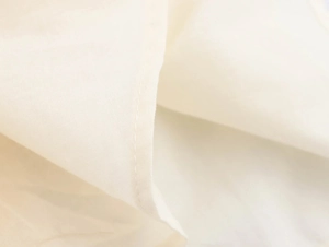 Detail of premium off-white cotton fabric with delicate stitching for summer dress