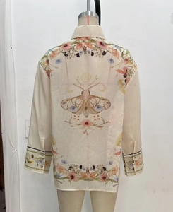 Detail of artistic moth and floral print on back of bohemian cream long sleeve shirt