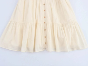 Detail of cream cotton-linen dress featuring wooden buttons and tiered pleat ruffles