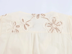 Detail view of floral embroidery and white lace on the beige cotton summer dress