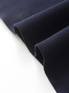 Macro shot showing the fine texture and drape of navy blue knitted blazer fabric