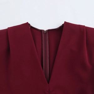 Detail of burgundy midi dress featuring deep V-neckline with pleated shoulders and hidden zipper