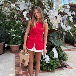 Women's red sleeveless buttoned vest paired with a polka dot skirt in a garden setting