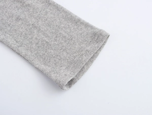 Dettaglio del polsino in maglia a coste e cuciture di questa maglia a maniche lunghe grigio chiaro