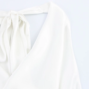 Close-up of elegant white satin halter top featuring a silk-like texture and bow tie neck