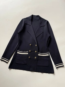 Detail of dark blue knit blazer with double-breasted gold buttons and white stripe accents