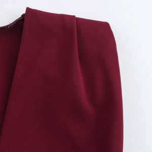 Close-up of pleated shoulder detail and woven fabric on a burgundy sleeveless midi dress
