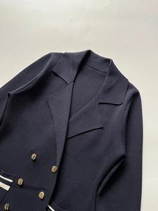 Detailed view of navy knit blazer featuring gold double-breasted buttons and white trim