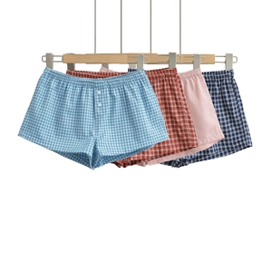 Detail view of cotton plaid boxer shorts featuring elastic waistbands and button fly details