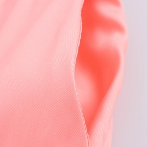 Gros plan sur la texture sergée fine et les coutures soignées de l'ensemble de chemise rose