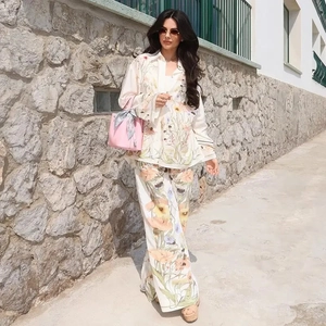 Detail view of women's loose-fit summer set featuring vibrant orange floral print on silky fabric