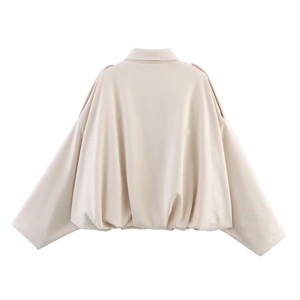 Détail d'une veste en daim beige avec manches chauve-souris et ourlet bouffant chic