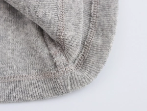 Dettaglio macro del tessuto a maglia grigio con cuciture fini e bordo a coste