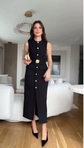 Détail d'une robe midi noire sans manches avec une ceinture et boucle dorée