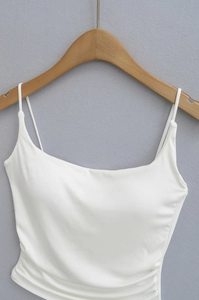 Detailed view of white knitted camisole with thin straps and side ruched design