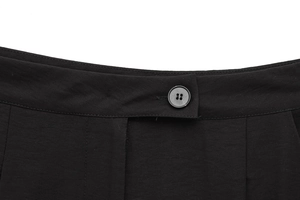 Dettaglio della vita di pantaloni neri a gamba dritta con chiusura a bottone singolo