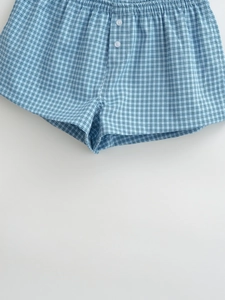 Detailed flat lay of blue checkered cotton boxer shorts with white button fly and elastic waist