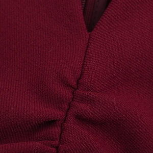 Macro texture of pleated burgundy fabric showing fine knit pattern and V-neck stitching