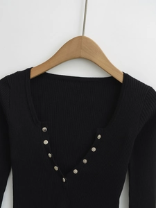 Detail of black ribbed knit cardigan featuring deep V-neckline and silver metal snap buttons