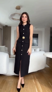 Détail montrant les boutons dorés et la ceinture assortie sur une robe midi noire sans manches