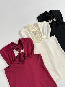 Detailed close-up of knit halter tops with gold metal hardware in burgundy, cream, and black